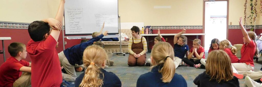 A group of elementary school children gather round to talk with artist Ashley Laverty