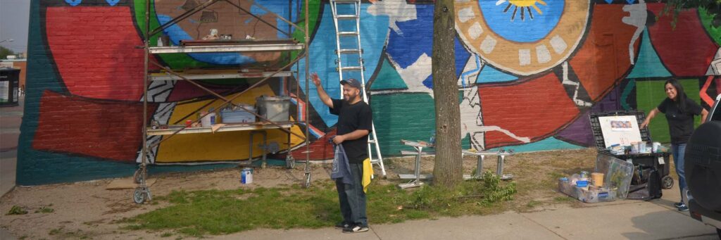 Artist working on a large-scale mural in South Omaha